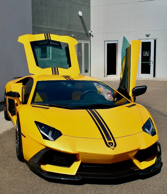 A bright yellow lamborghini with doors open.